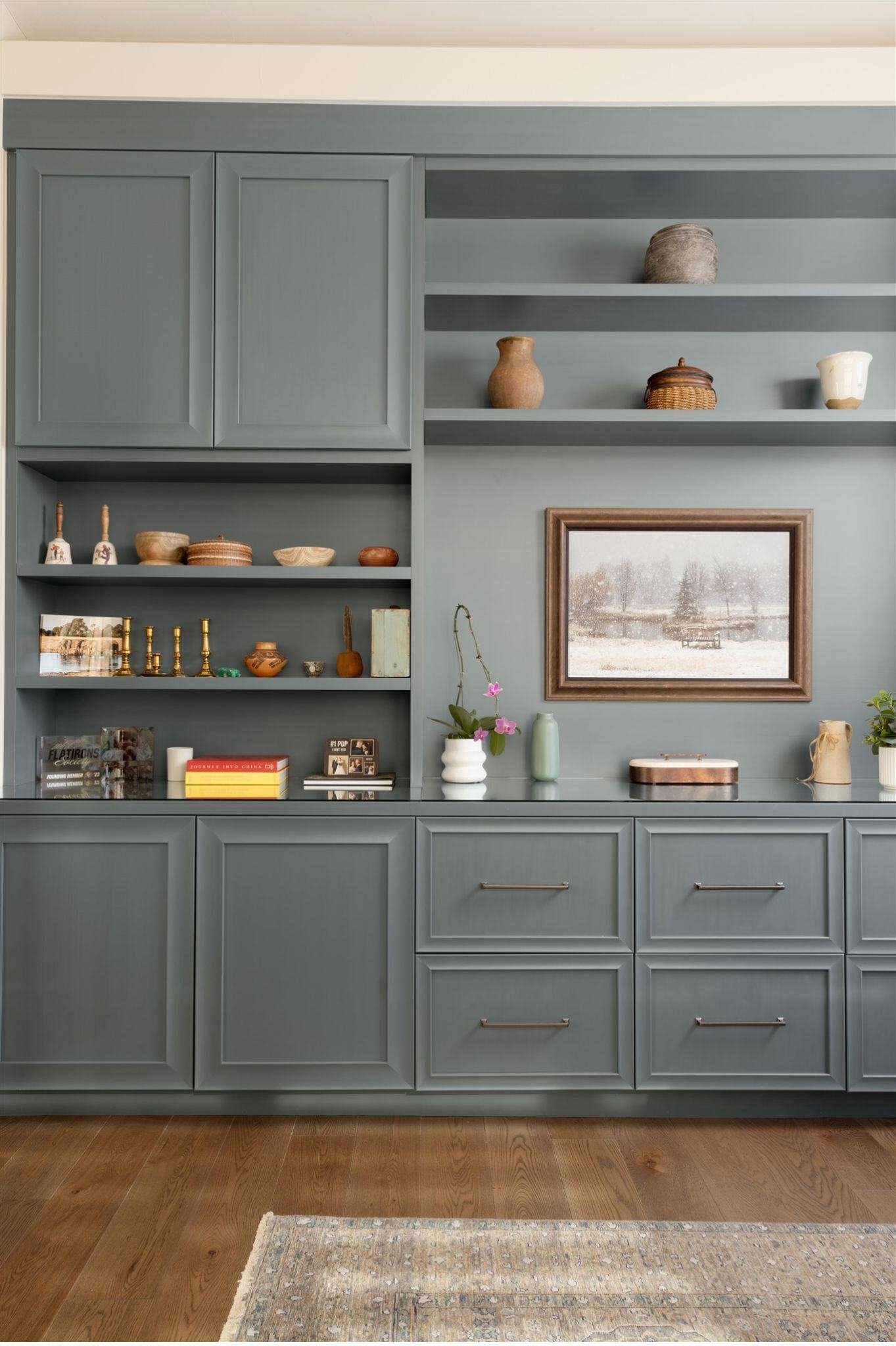 custom built in wall storage with blue drawers, cabinets, and shelves and dark wood floors