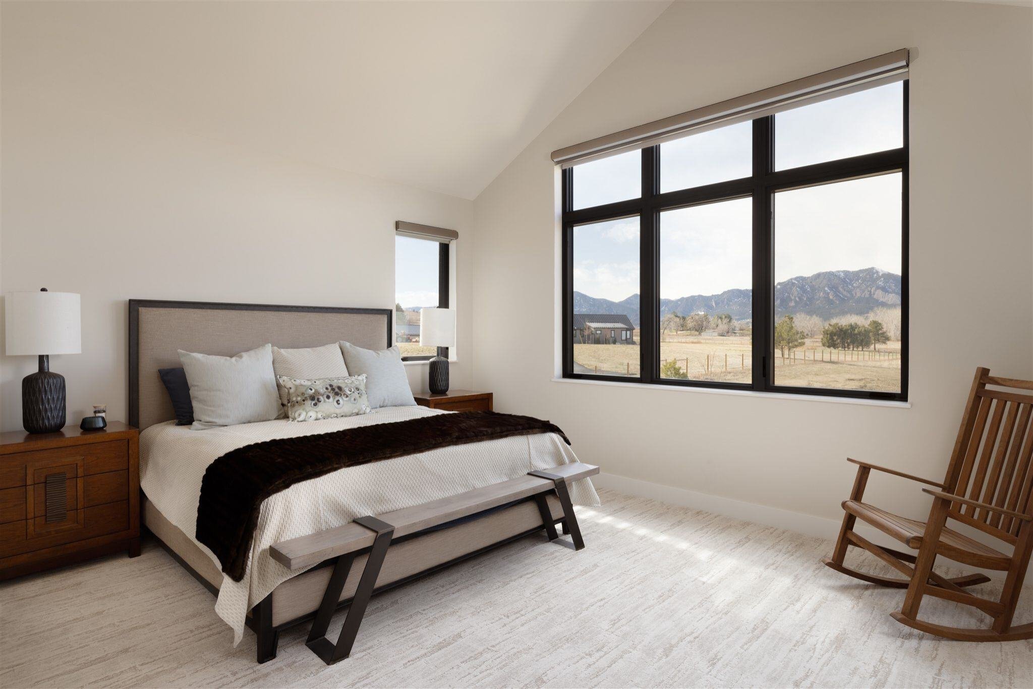 white bedroom in in a custom built colorado home with mountain views featuring slanted ceilings, rocking chair, and bed
