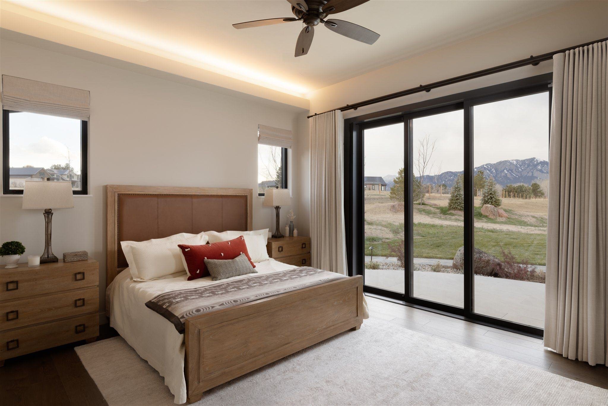 colorado bedroom with mountain views, slider doors to patio, and black ceiling fan