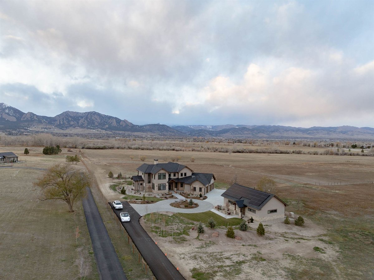 drone shot of a large custom built home in colorado with mountain view and an adu on large property