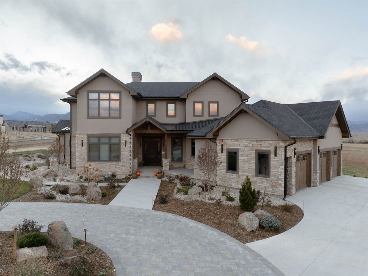 custom built home in colorado with 3 car garage, tan stone exterior, and gray stone driveway pavers