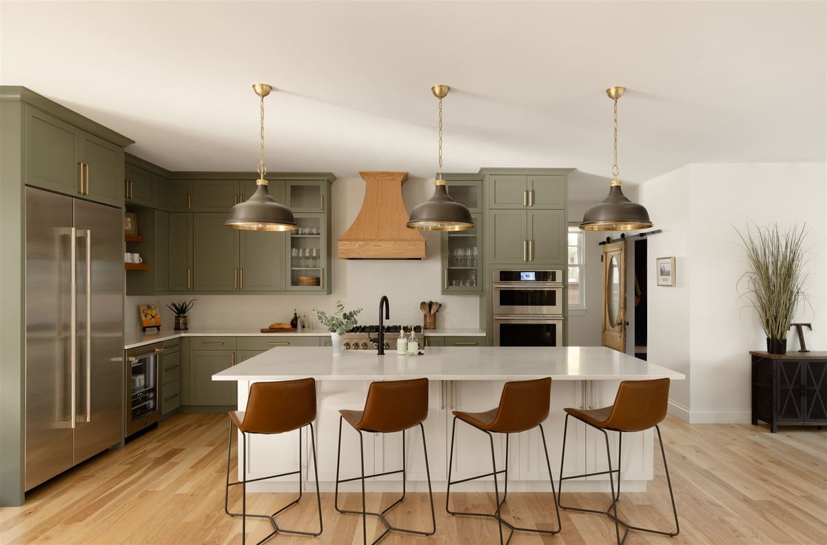 Colorado kitchen remodel with green cabinets, white kitchen island, car stool seating, and light wood floors and kitchen hood