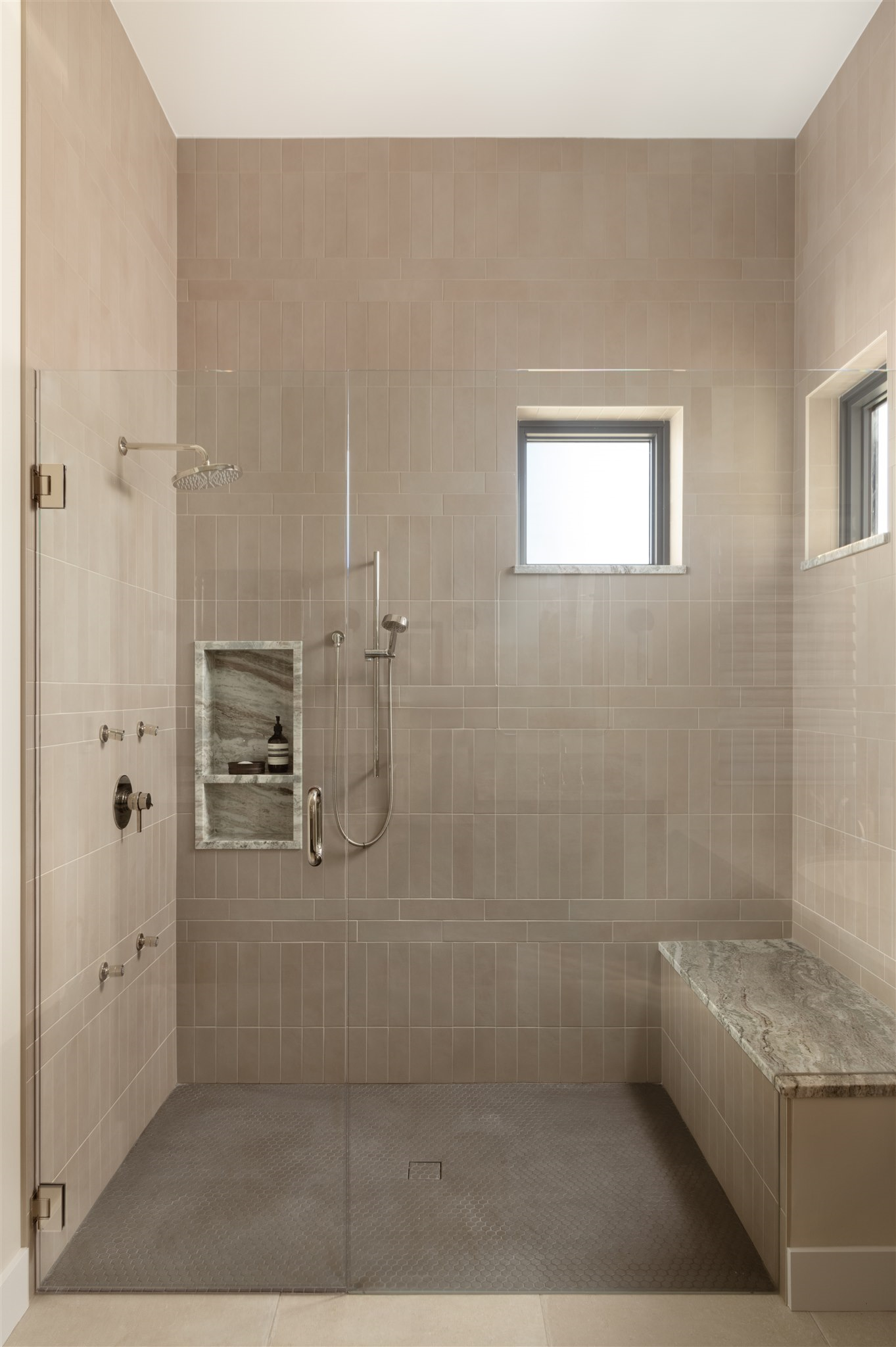 walk in shower with bench and modern but neutral tile design 