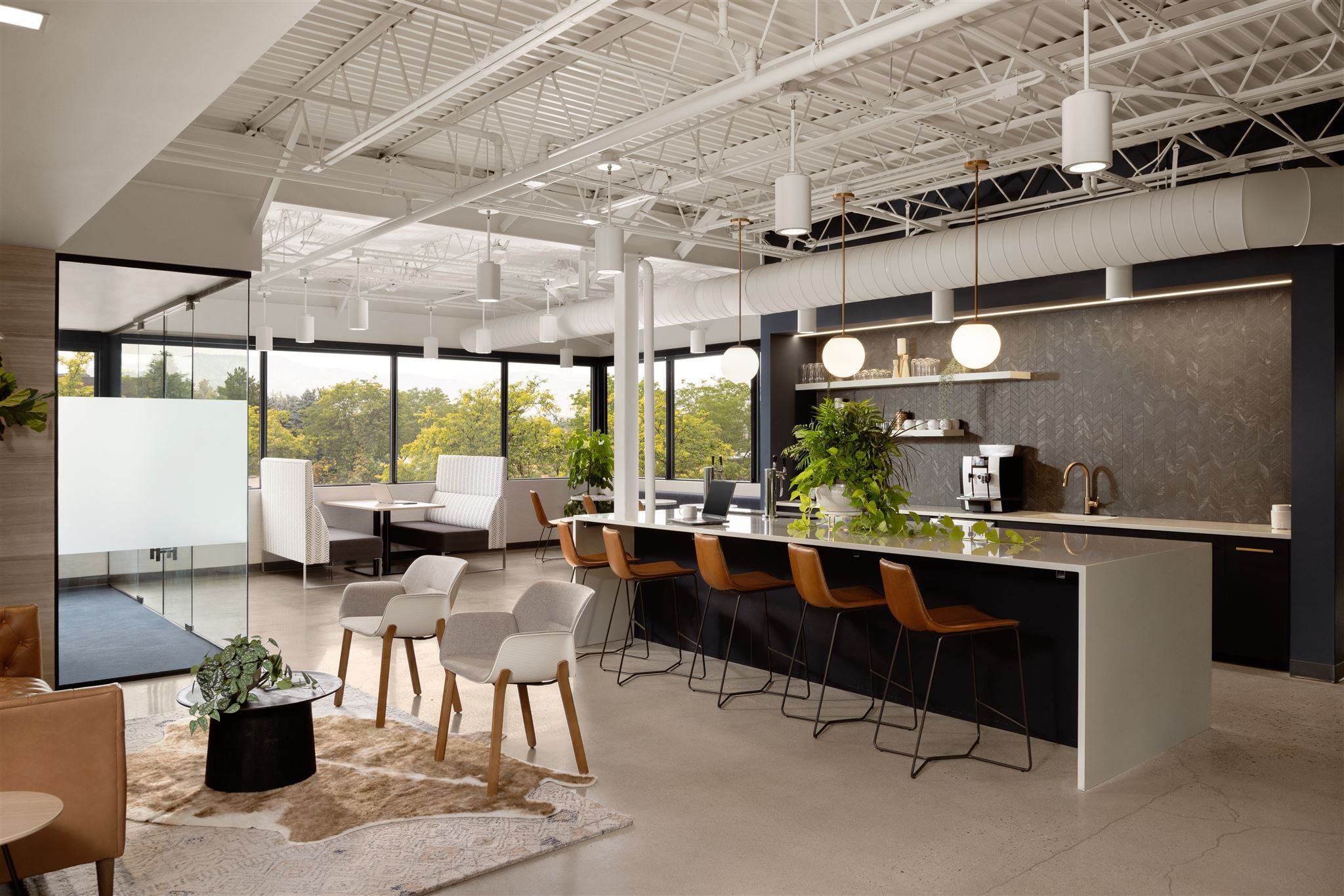 Coffee bar in a modern Colorado office with kitchen island seating, modern appliances, and a cozy seating area