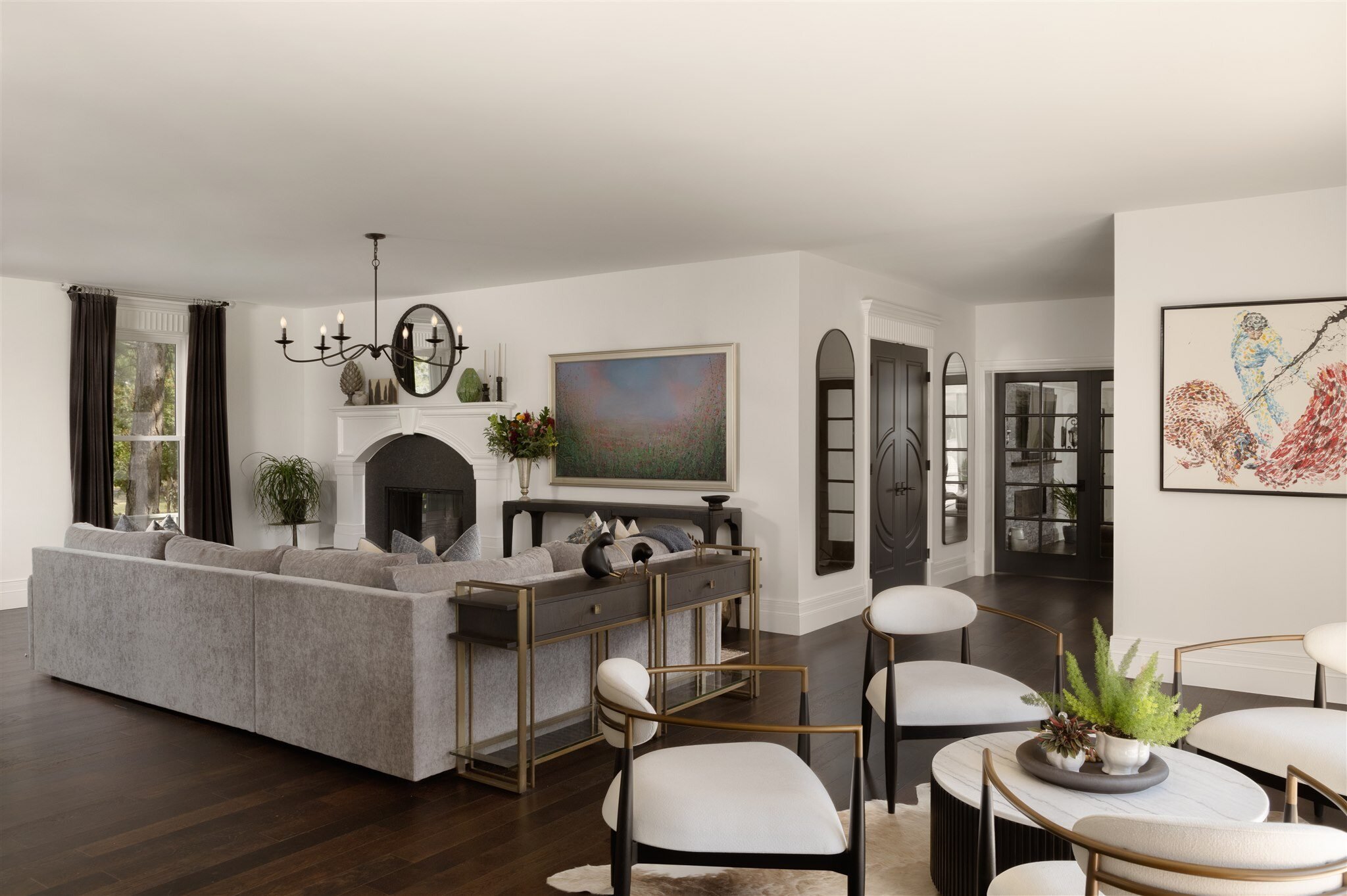 Living room with dark floors, white walls, and framed art with gray sectional and a white fireplace