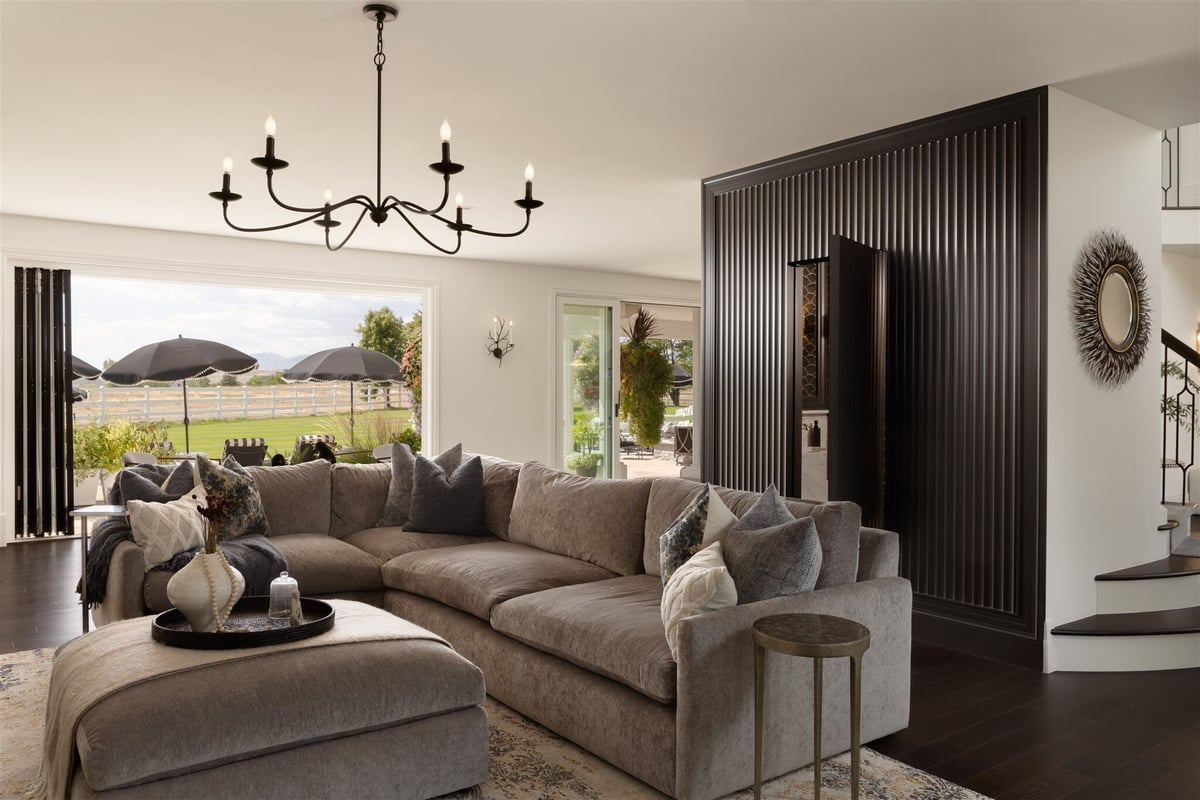 Custom living room remodel in Colorado with dark textured wall, black floors, and a black chandelier