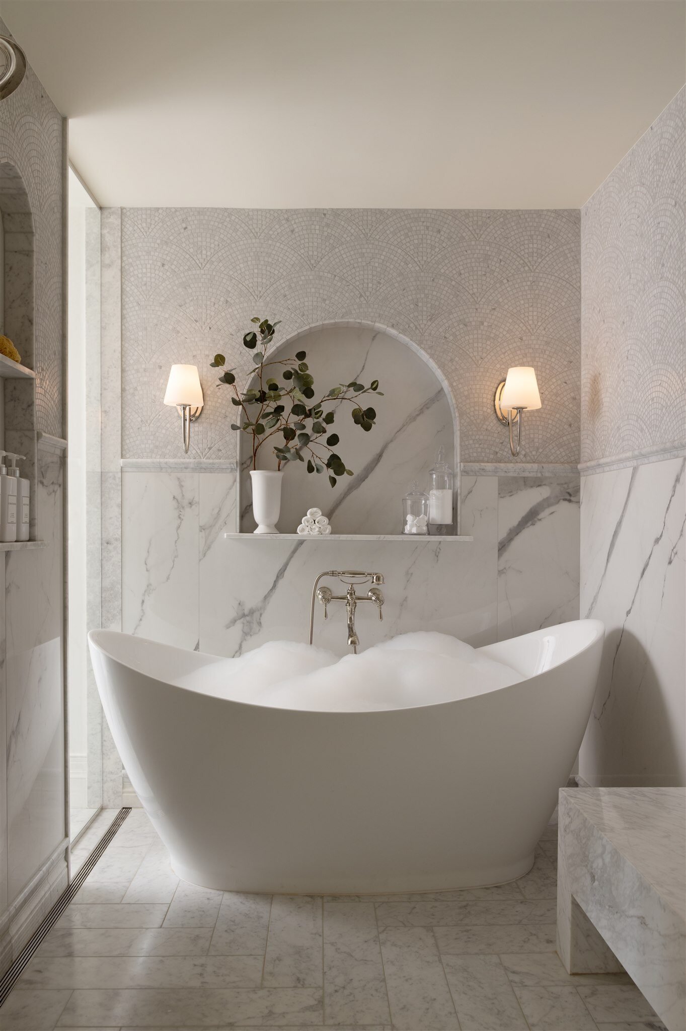 freestanding white bath tub with white marble floors and custom lighting