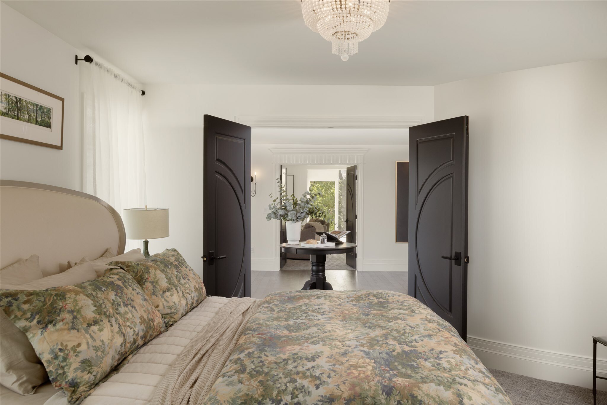 primary bedroom with double black doors and a chandelier