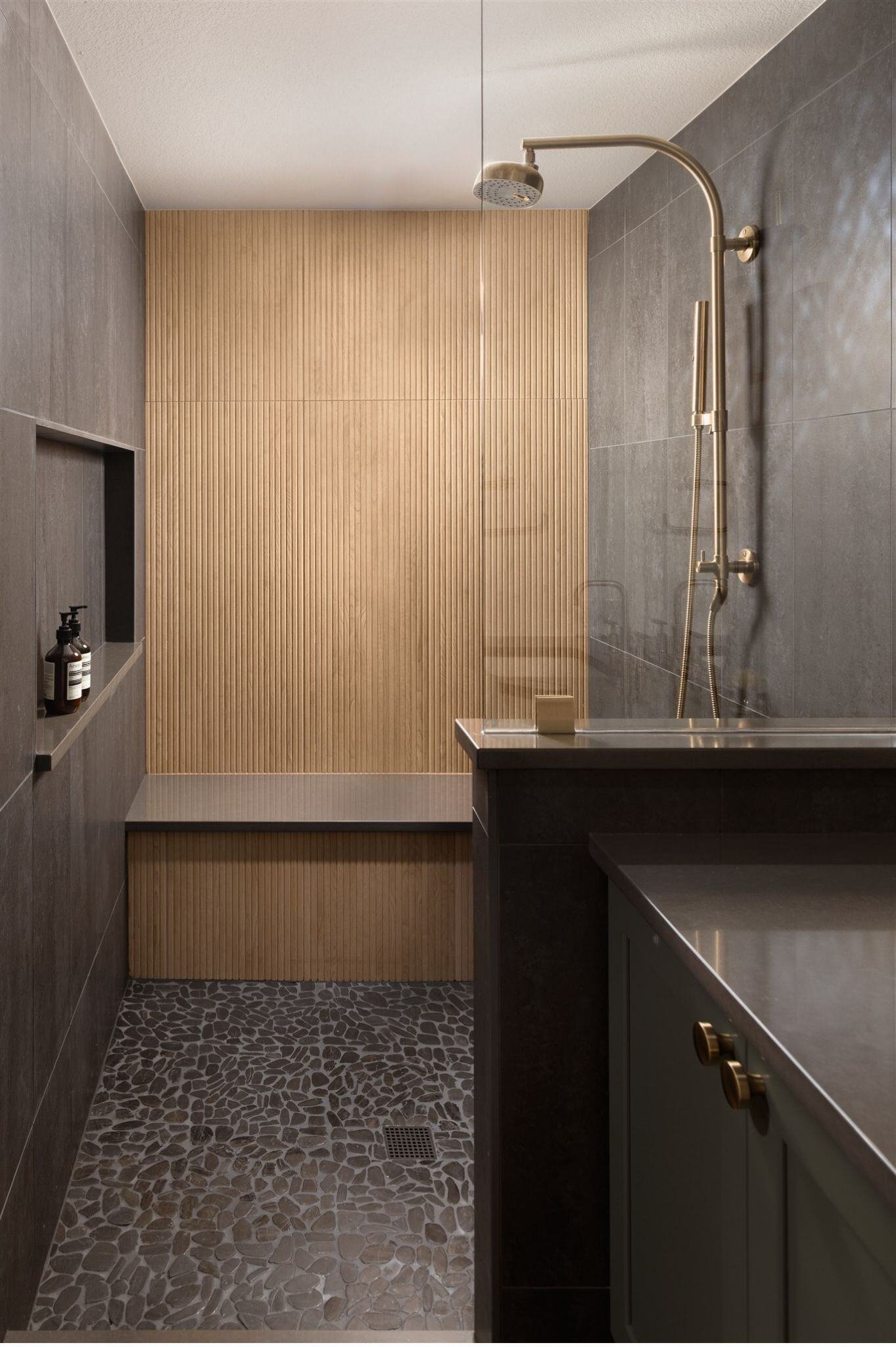 shower remodel with pebble shower floor, built-in bench, and dark tile in boulder colorado